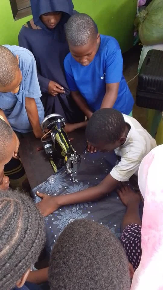 Young learners practising sewing together at The Impact Crew TZ — session 2