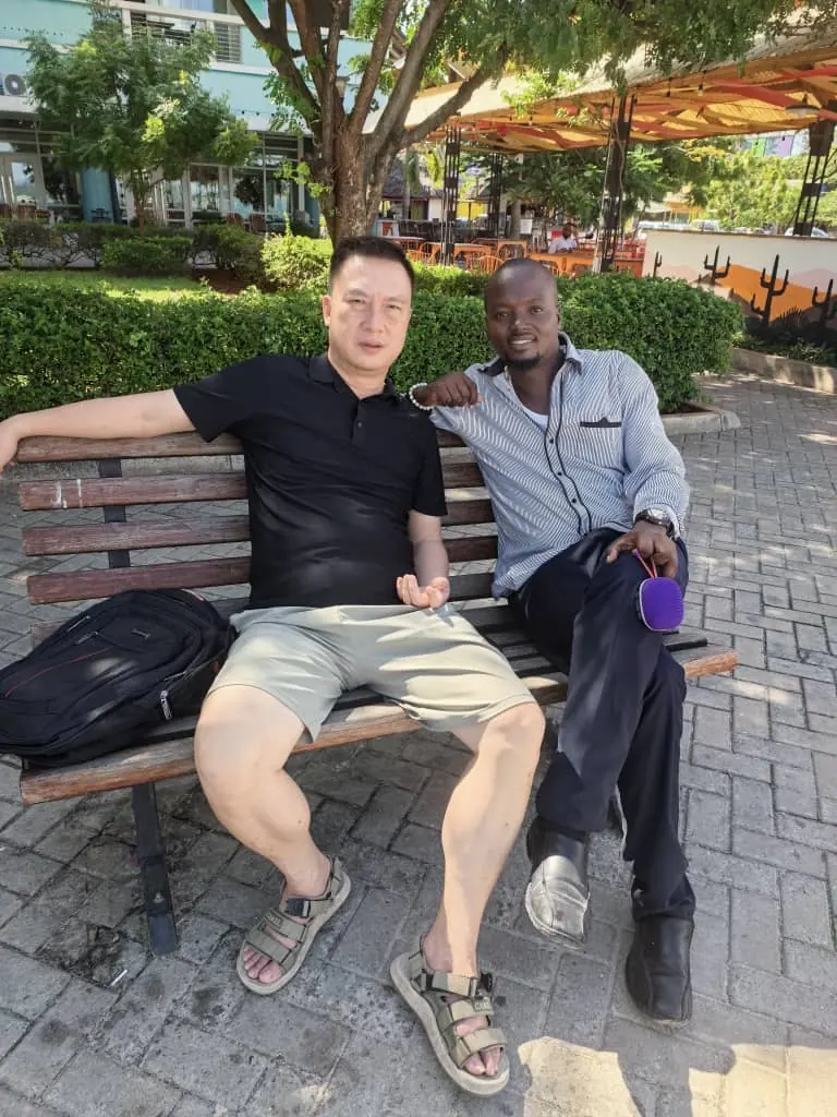 A visitor and a local guide sitting and smiling together on a park bench