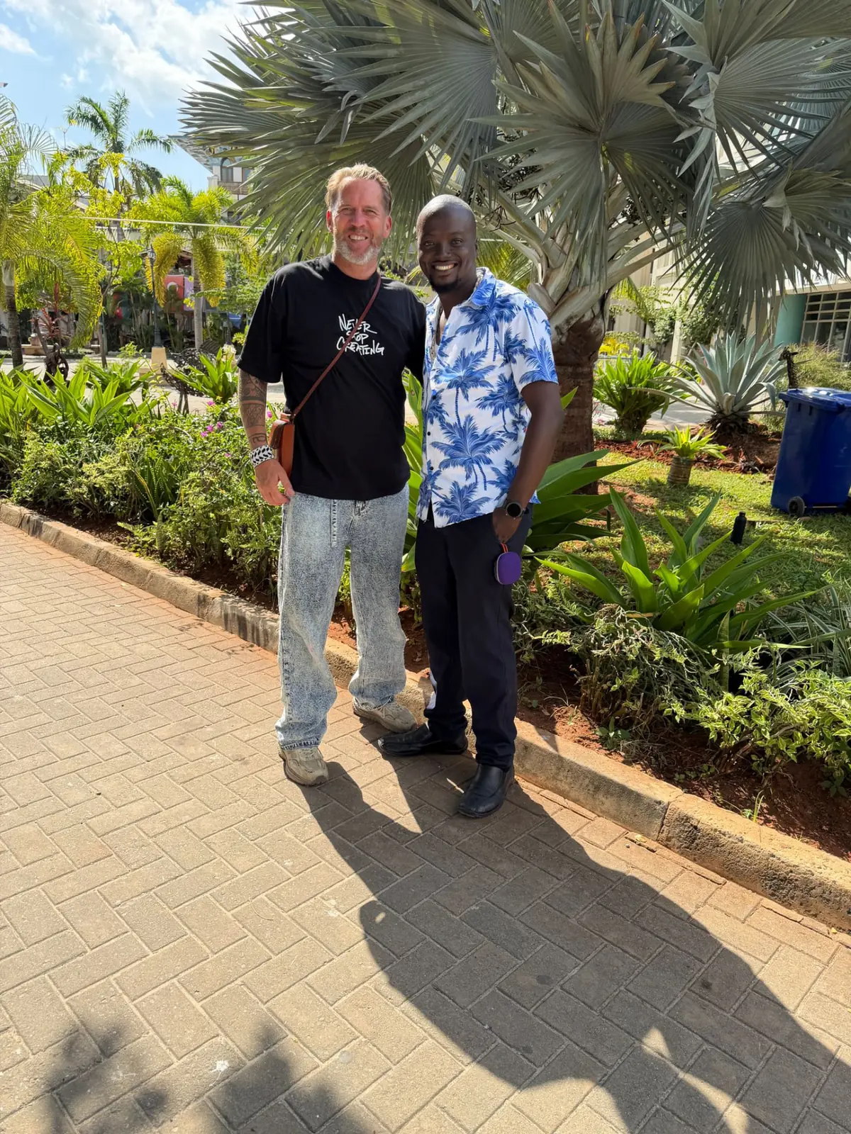 A visitor and a Tanzania World Link guide walking and smiling in a tropical garden