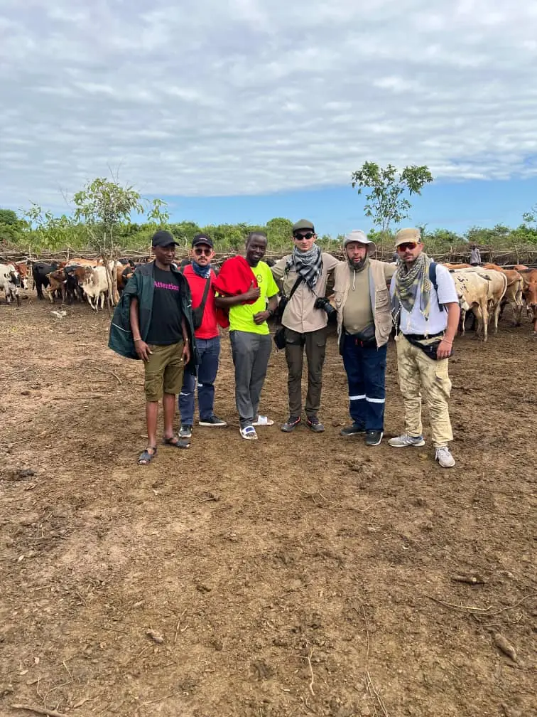 Visitors and local guides standing together in front of a Maasai cattle camp